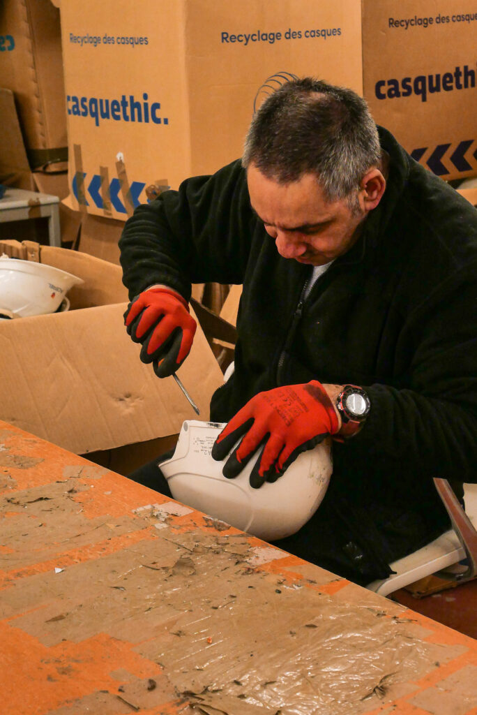 Salarié en situation de handicap qui démantèle un casque de chantier